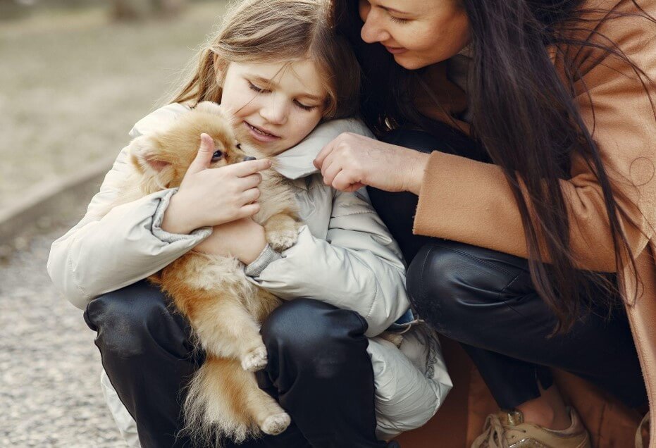 mother and daughter playing with a pomeranian in the park